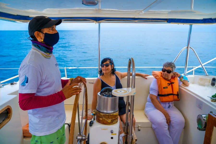 Mujeres viajando en Velero, de fondo el mar y un guía explicando la experiencia